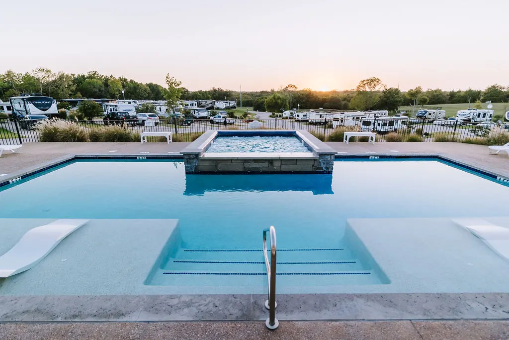 Resort pool and hot tub at sunset with the Farmhouse lit behind
